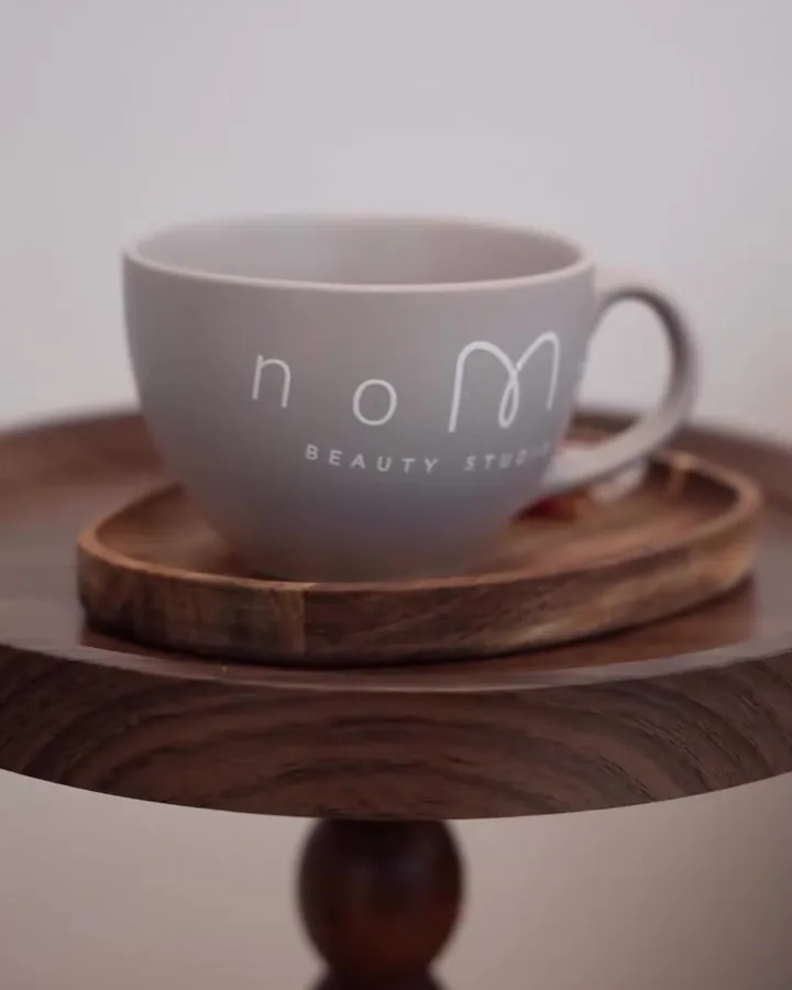 Tasse mit dem noMa-Logo auf einem Holzbrett